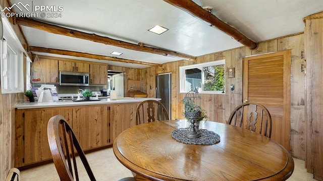 dining space with wood walls, baseboard heating, and beam ceiling