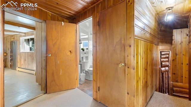 corridor with wood walls, lofted ceiling, wooden ceiling, and a baseboard heating unit