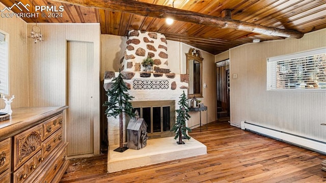 interior space with wooden ceiling, a stone fireplace, a baseboard heating unit, wooden walls, and light wood-type flooring