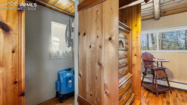 interior space featuring wooden ceiling, beam ceiling, wooden walls, light hardwood / wood-style flooring, and a baseboard radiator