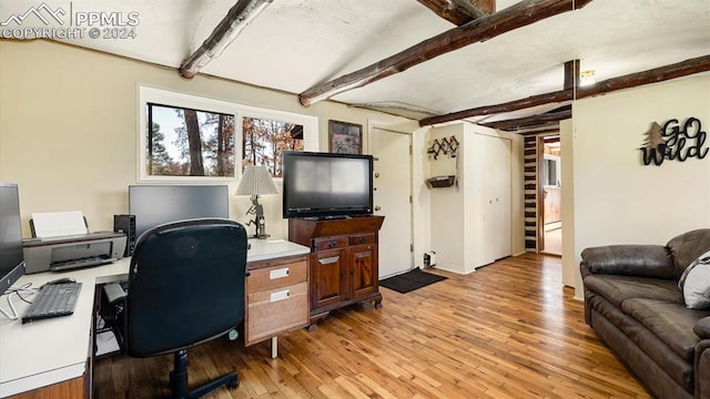 office with beam ceiling and light hardwood / wood-style flooring