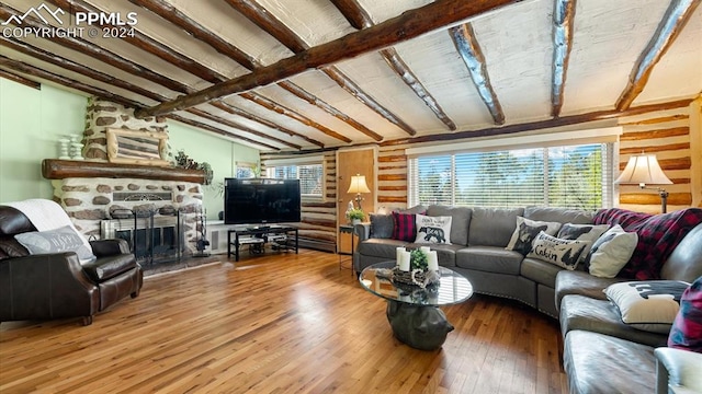 living room featuring a stone fireplace, hardwood / wood-style flooring, and beam ceiling