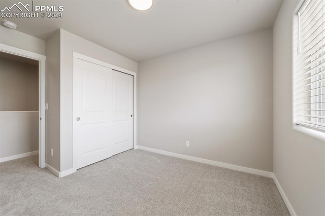 unfurnished bedroom featuring light carpet and a closet