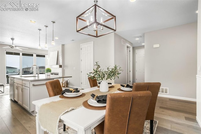 dining area featuring light hardwood / wood-style floors, ceiling fan with notable chandelier, and sink