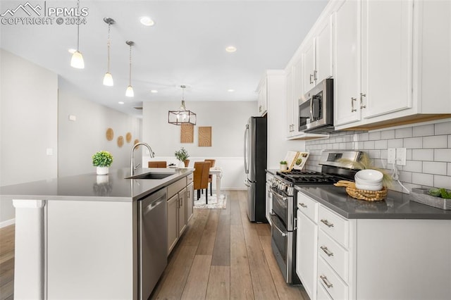 kitchen with appliances with stainless steel finishes, decorative light fixtures, sink, an island with sink, and white cabinets