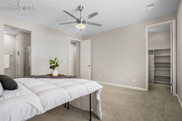 bedroom with a walk in closet, light carpet, and ceiling fan