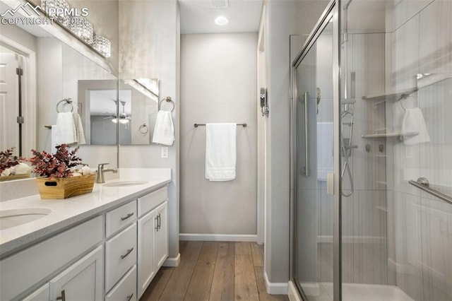 bathroom featuring wood-type flooring, ceiling fan, vanity, and a shower with shower door