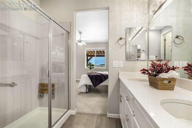 bathroom featuring hardwood / wood-style floors, a shower with door, vanity, and ceiling fan