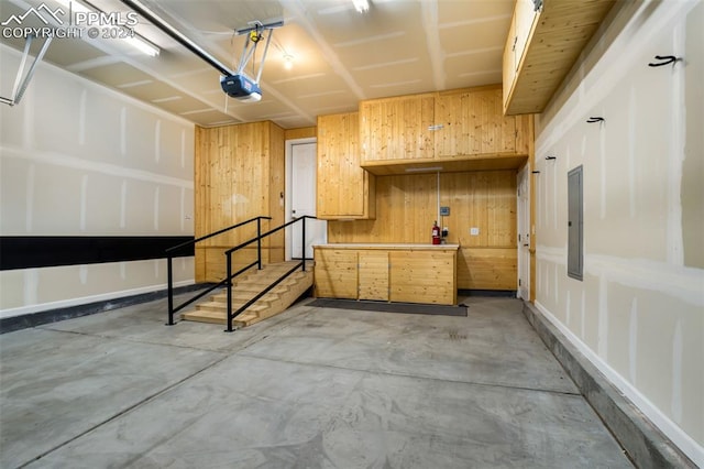 garage with electric panel, a garage door opener, and wooden walls