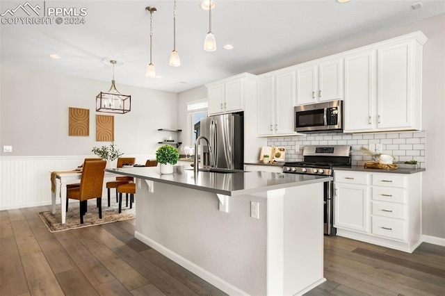 kitchen featuring a kitchen island with sink, decorative light fixtures, dark hardwood / wood-style floors, and stainless steel appliances