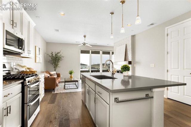 kitchen with stainless steel appliances, dark wood-type flooring, sink, a kitchen island with sink, and white cabinetry