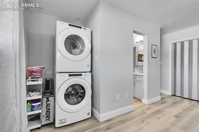 laundry area featuring light hardwood / wood-style flooring, stacked washer / drying machine, and sink