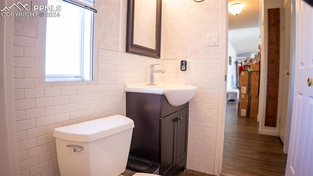 bathroom with toilet, vanity, wood-type flooring, and tile walls