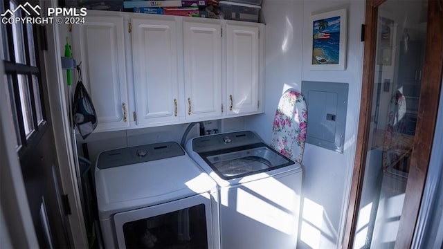 washroom featuring cabinets, electric panel, and washer and clothes dryer