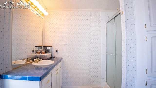 bathroom featuring vanity, crown molding, a textured ceiling, and a shower with shower door