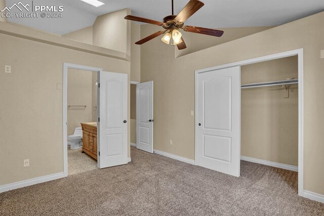 unfurnished bedroom with ensuite bathroom, ceiling fan, a towering ceiling, light colored carpet, and a closet