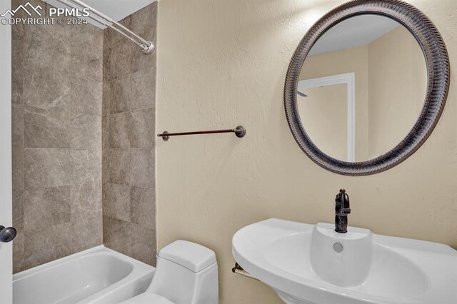 full bathroom featuring tiled shower / bath combo, toilet, and sink