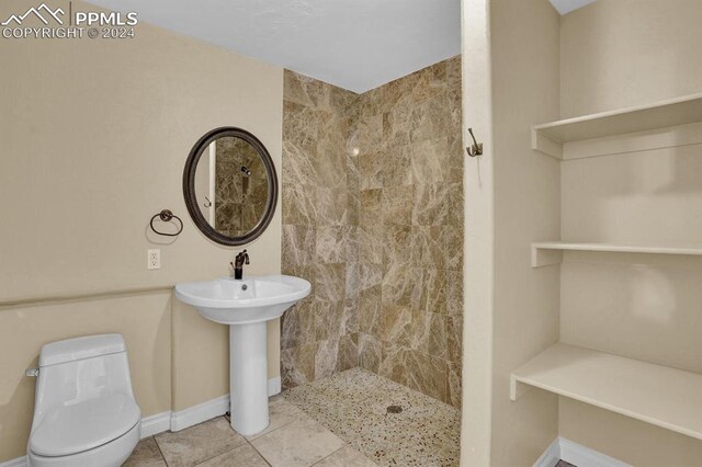 bathroom with tile patterned floors, toilet, and tiled shower