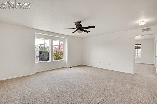 empty room with light carpet, a healthy amount of sunlight, and ceiling fan