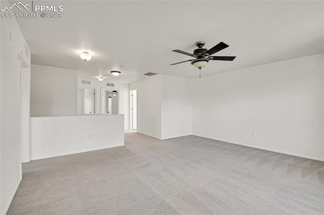 empty room featuring ceiling fan and light colored carpet