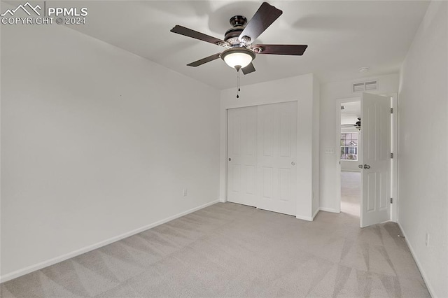 unfurnished bedroom featuring light carpet, a closet, and ceiling fan