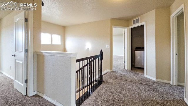 hallway with washer / dryer, carpet floors, and a textured ceiling