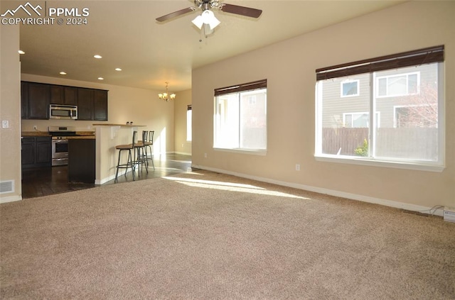 unfurnished living room featuring ceiling fan with notable chandelier and dark carpet