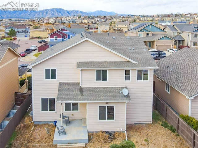 back of property with a mountain view and a patio area