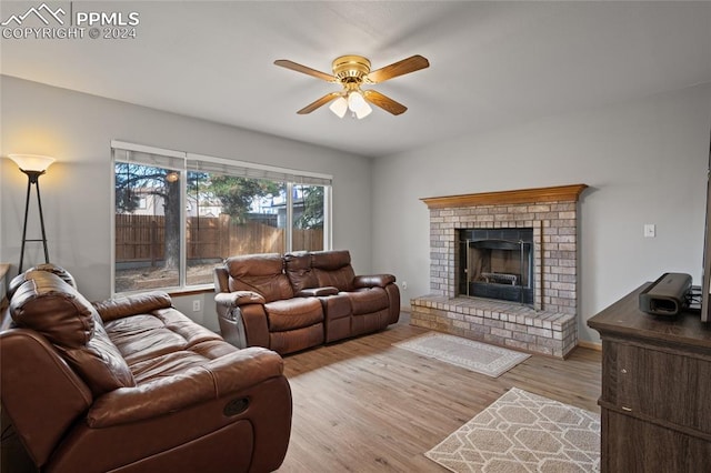 living room with a fireplace, light hardwood / wood-style floors, and ceiling fan