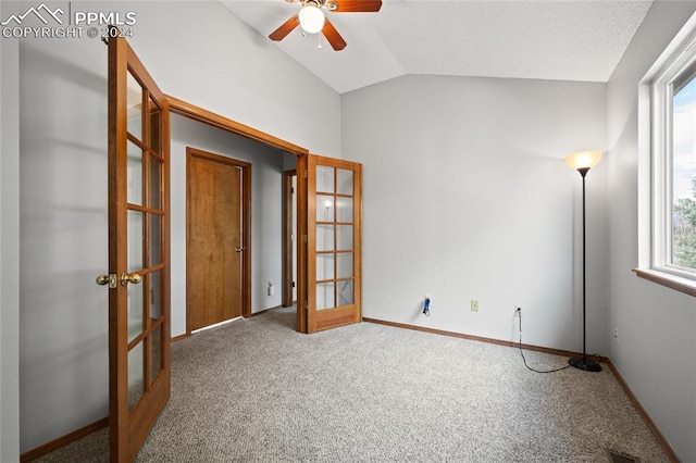 carpeted spare room with french doors, plenty of natural light, and lofted ceiling