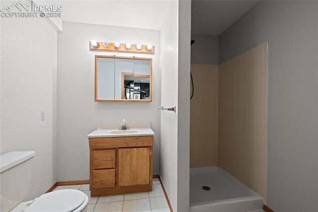 bathroom featuring toilet, vanity, tile patterned floors, and a tile shower