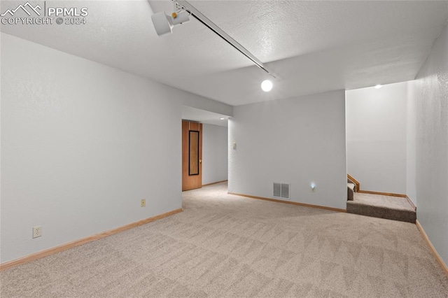 unfurnished room with a textured ceiling and light carpet