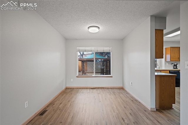 unfurnished dining area with light hardwood / wood-style floors and a textured ceiling