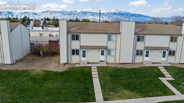 rear view of property with a mountain view and a lawn