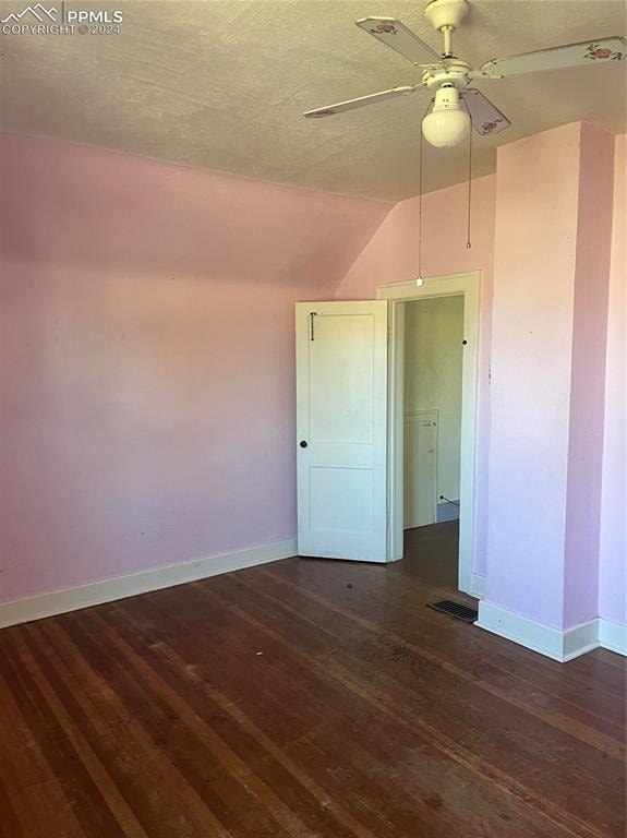 empty room featuring dark wood-type flooring, ceiling fan, a textured ceiling, and lofted ceiling