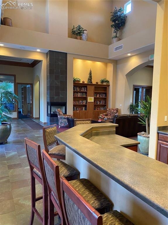 interior space featuring a towering ceiling and a tiled fireplace