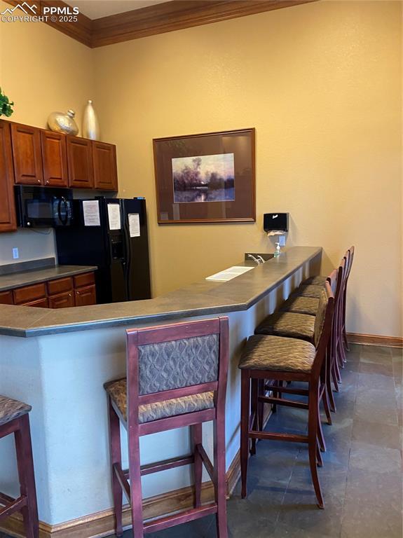 kitchen featuring a breakfast bar, kitchen peninsula, black appliances, and crown molding