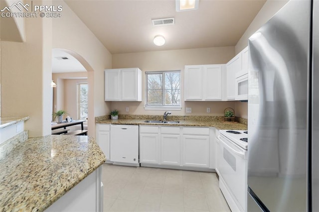 kitchen with sink, white appliances, white cabinetry, light stone countertops, and plenty of natural light