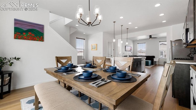 dining space with ceiling fan with notable chandelier, light wood-type flooring, and sink