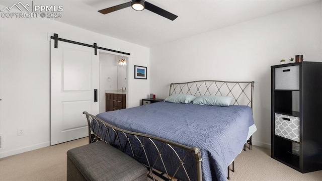 carpeted bedroom featuring a barn door, ensuite bathroom, and ceiling fan