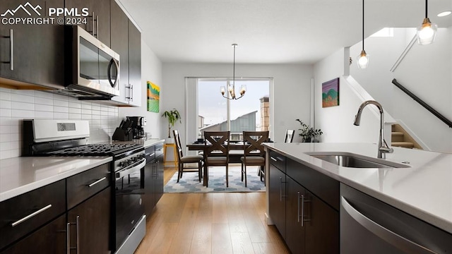 kitchen with sink, hanging light fixtures, stainless steel appliances, light hardwood / wood-style flooring, and a chandelier