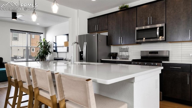 kitchen with a center island with sink, stainless steel appliances, and light wood-type flooring