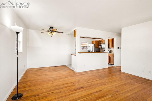 unfurnished living room featuring ceiling fan and light wood-type flooring