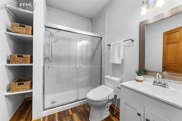 bathroom featuring walk in shower, vanity, wood-type flooring, and toilet