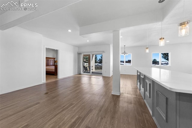 unfurnished living room featuring a chandelier, dark hardwood / wood-style flooring, and a healthy amount of sunlight