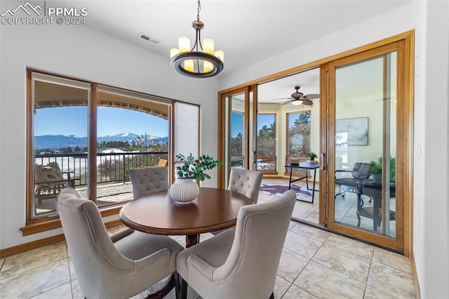 dining area with a water and mountain view and ceiling fan with notable chandelier