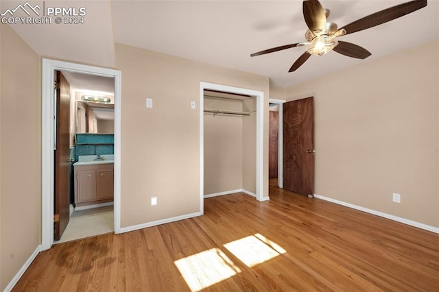 unfurnished bedroom featuring ceiling fan, connected bathroom, light hardwood / wood-style floors, a closet, and sink