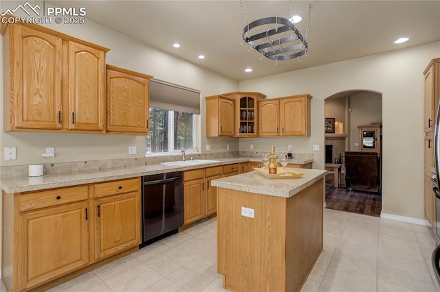 kitchen featuring a center island, arched walkways, a sink, black dishwasher, and light countertops