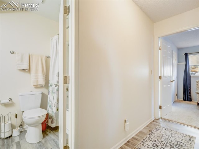 bathroom featuring a textured ceiling, hardwood / wood-style flooring, and toilet