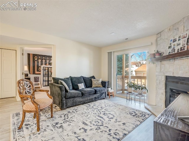 living room with a fireplace, light hardwood / wood-style floors, and a textured ceiling